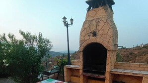 Ein Außenbereich mit Grill, einem Steinofen, einem Tisch mit Tischdecke und einer Lampe.