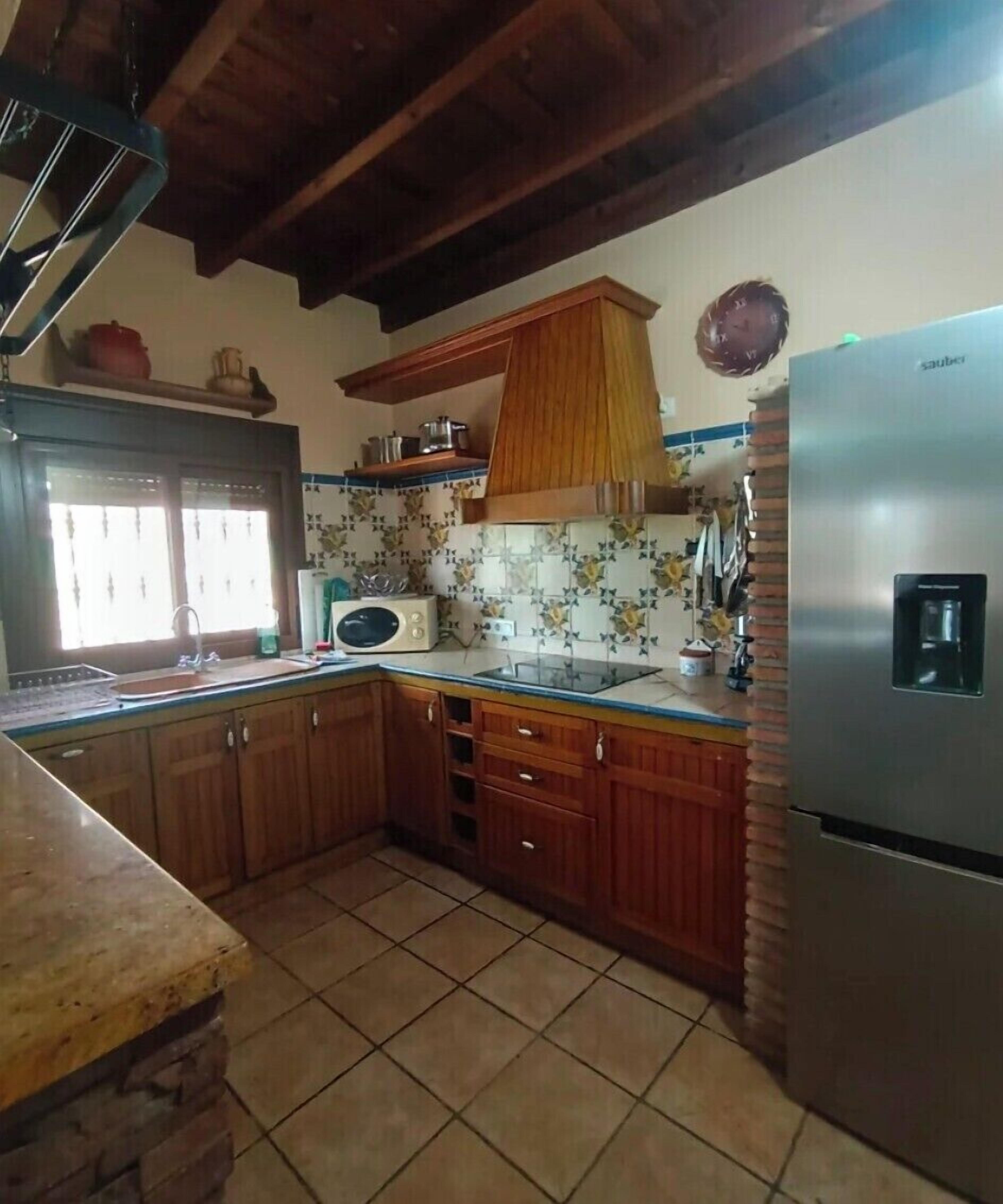 A kitchen with wooden cabinets, a tiled floor, a refrigerator, and a microwave.