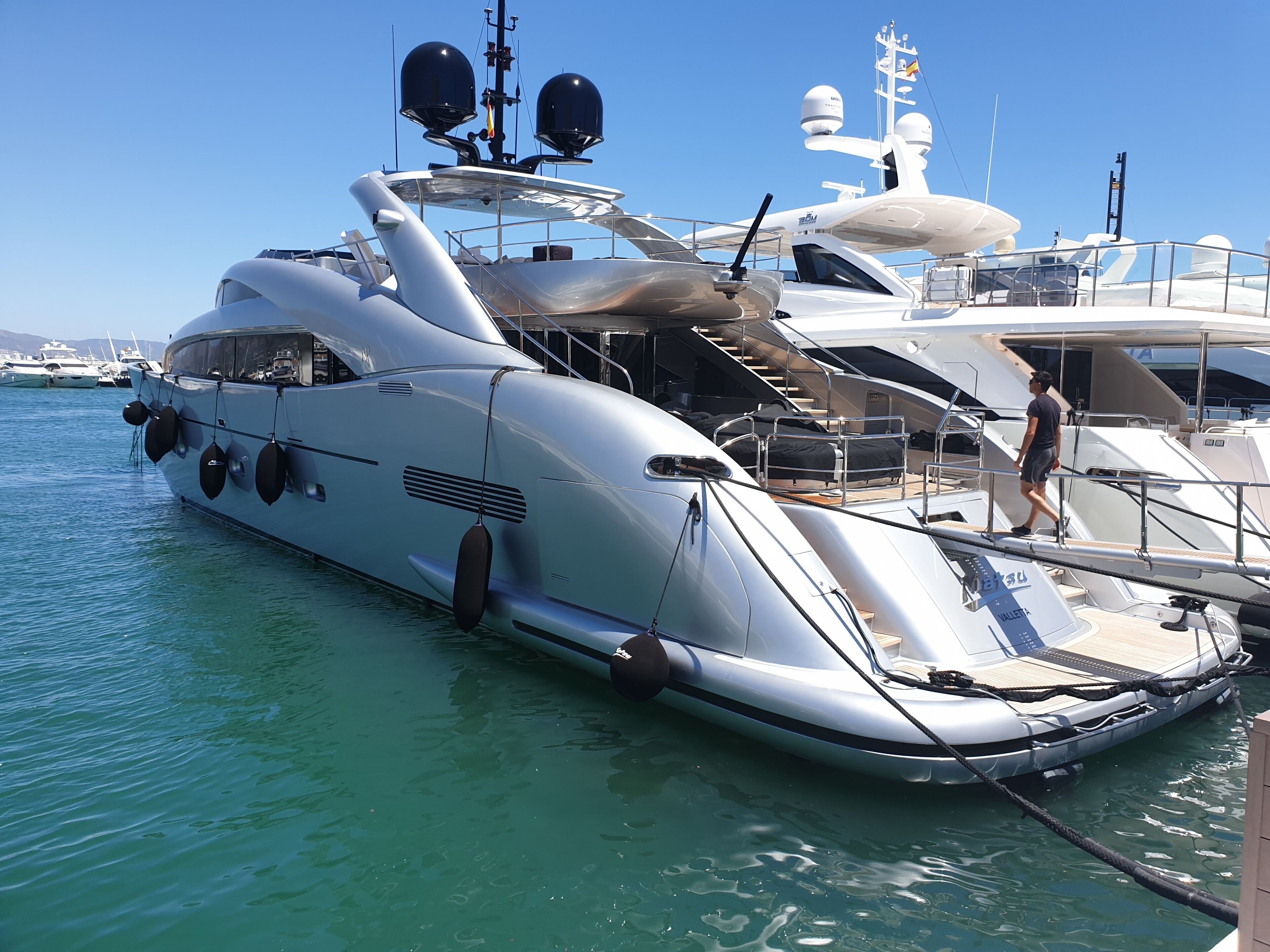 Un yate grande amarrado en un puerto deportivo, con varias cubiertas y un helipuerto.