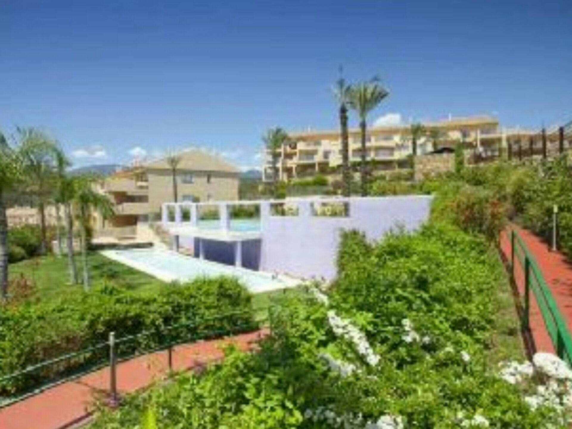 Et resort med pool, frodig beplantning og flere bygninger.