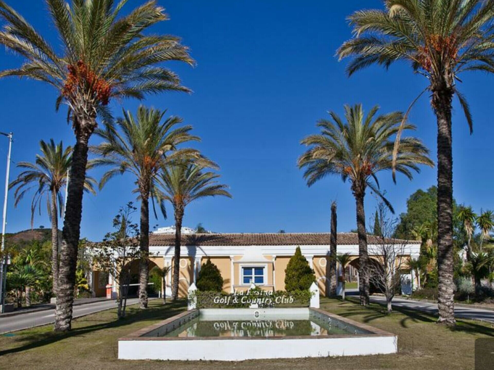 A golf and country club with palm trees and a clear blue sky.