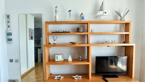 Una sala de estar moderna con un mueble de televisión de madera, un televisor de pantalla plana y varios objetos decorativos.