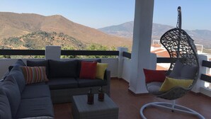 A balcony with a sofa and a hanging chair, offering a view of distant hills. - Casa de Mairena - Sea/Mountain Views + Infinity Pool (Marbella)