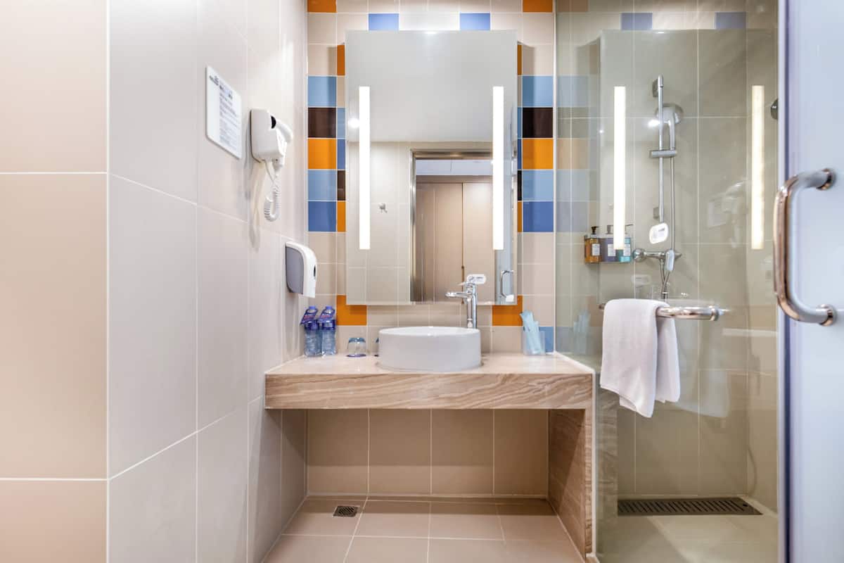 A modern bathroom with a sink, mirror, and glass shower enclosure.