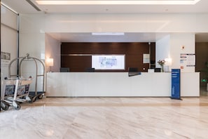 A hotel reception area with a modern design, including a reception desk, a digital screen, and a clean, tiled floor. - Holiday Inn Express Liuyang Development Zone by IHG (Changsha)