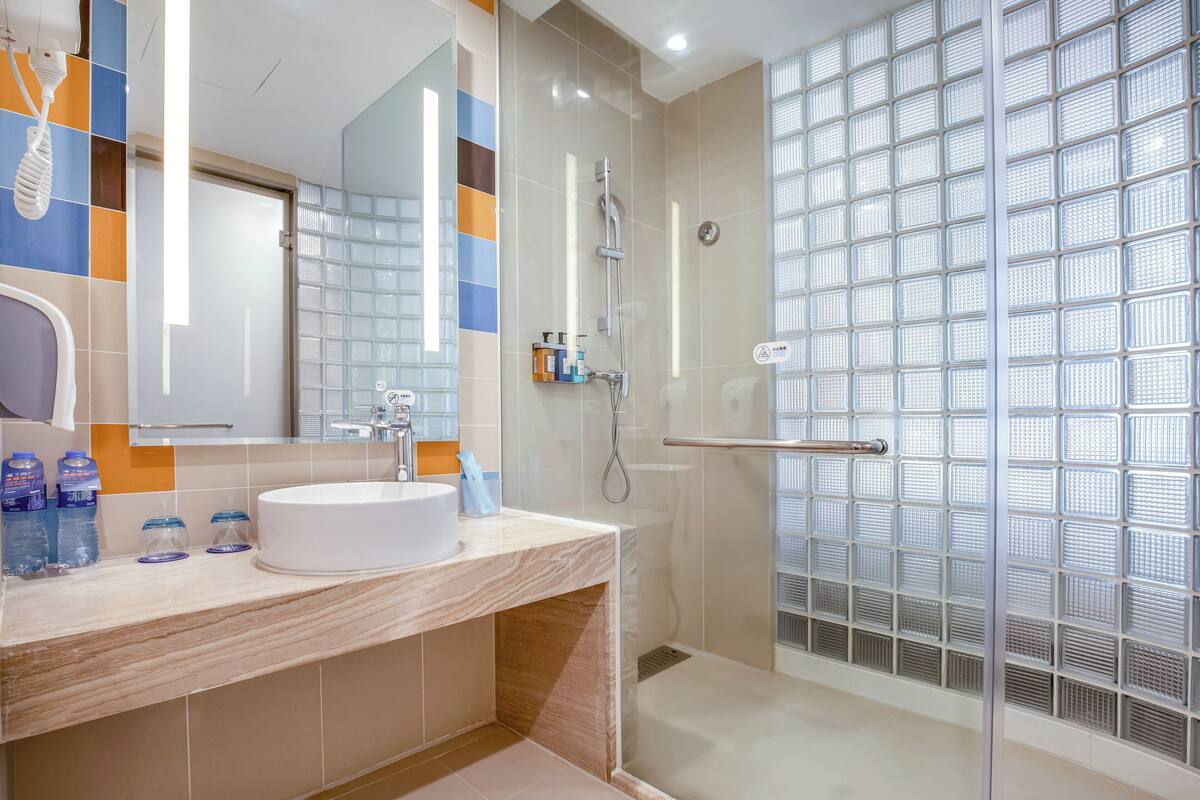 A modern bathroom with a white sink, a glass shower enclosure, and a tiled backsplash.