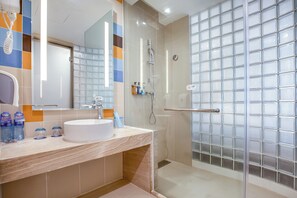 A modern bathroom with a white sink, a glass shower enclosure, and a tiled backsplash.