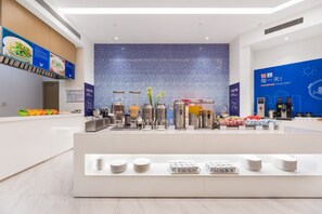 A modern hotel lobby with a central counter displaying various amenities, including a coffee machine, kettles, and a fruit display. - Holiday Inn Express Liuyang Development Zone by IHG (Changsha)