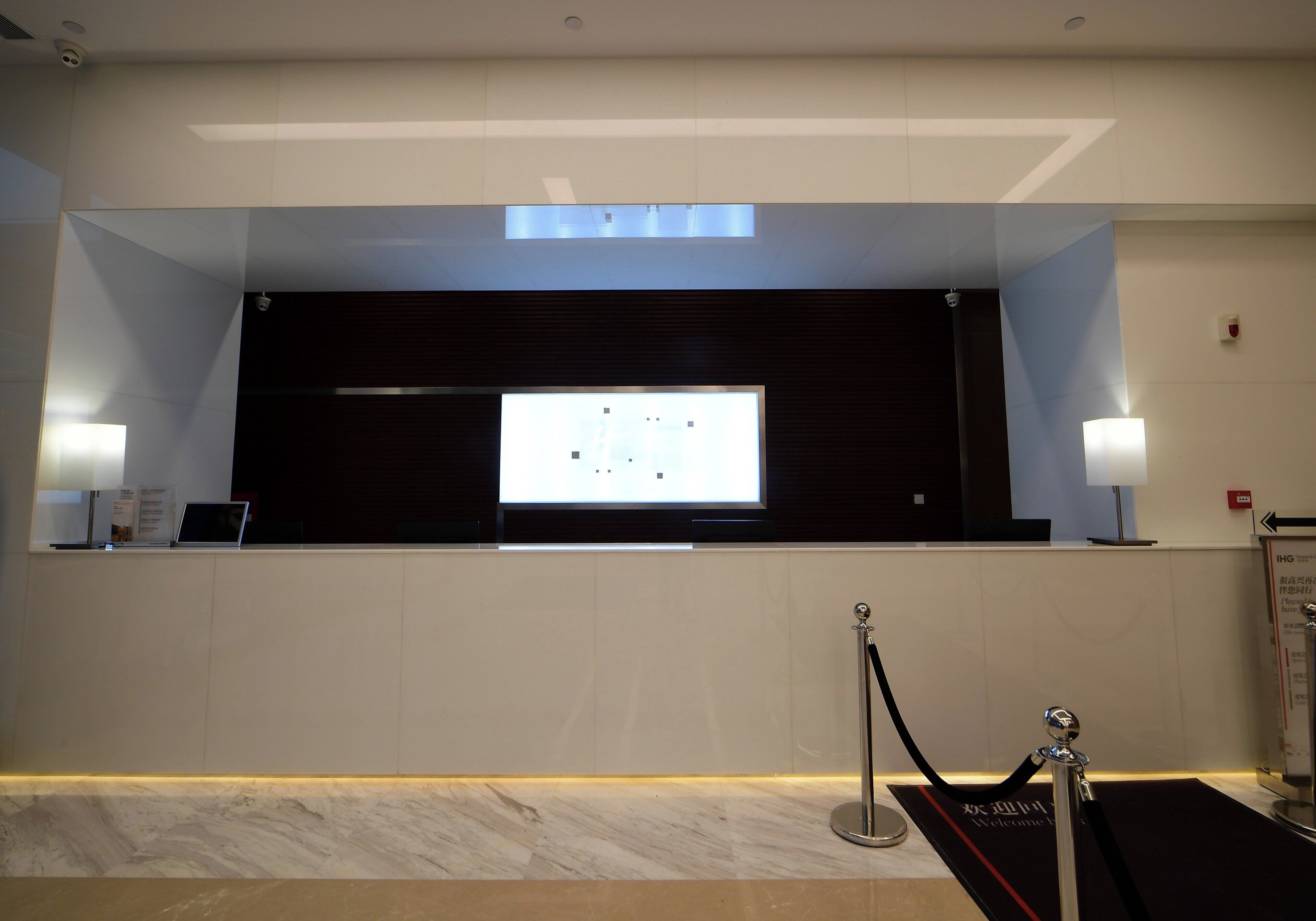 A reception area with a large screen, a desk, and a security checkpoint.