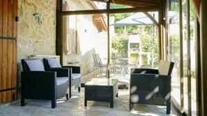 Un patio al aire libre con mobiliario de mimbre y suelo de piedra.