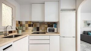 Een moderne keuken met witte kastjes, een magnetron en een koelkast.