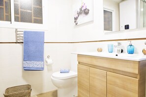 A bathroom with a white toilet, a blue towel, a wooden vanity, and a mirror above the sink.