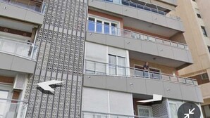 A multi-story residential building with balconies, a central vertical feature, and a clock.