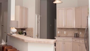 Una cocina moderna con una isla central, taburetes de madera y una zona de comedor con mesa.