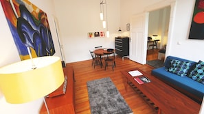 A living room with a blue sofa, wooden coffee table, and a painting on the wall.