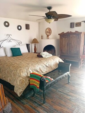 A bedroom with a bed, a bench, a wooden cabinet, and a ceiling fan.