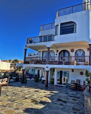 A multi-story building with balconies, outdoor seating, and potted plants.