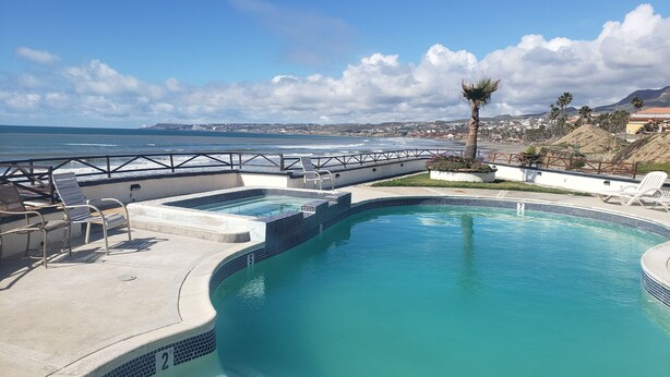 A swimming pool with a view of the ocean and a cityscape in the background.