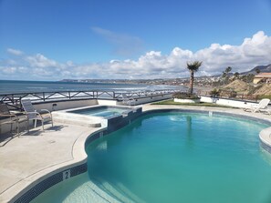 A swimming pool with a view of the ocean and a cityscape in the background.