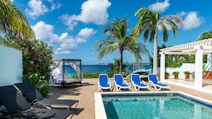 A poolside area with lounge chairs, a canopy, and a view of the ocean. - Tropical oceanfront villa, full AC, private pool, great diving and snorkeling (Kralendijk)