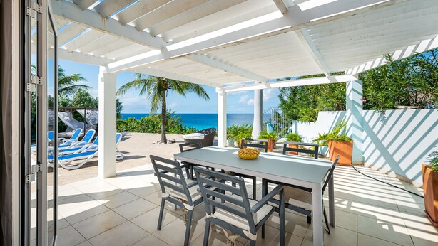 A covered patio with a table and chairs, overlooking a pool and the ocean. - Tropical oceanfront villa, full AC, private pool, great diving and snorkeling (Kralendijk)