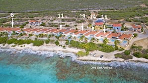 An aerial view of a coastal resort with multiple villas, a beach, and clear turquoise waters. - Tropical oceanfront villa, full AC, private pool, great diving and snorkeling (Kralendijk)
