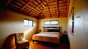 Une chambre à coucher avec un lit en bois, une chaise et un toit de chaume.
