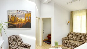 A modern living room with a sofa, a chair, a TV mounted on the wall, and a large window with curtains. -  AWESOME loc'n by Operahouse, charming Apartment, Lux on budget (Budapest)