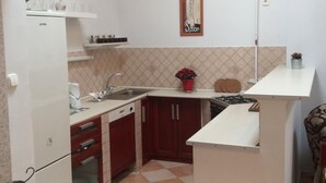 A compact kitchen with a dining area, featuring a refrigerator, sink, cabinets, and a dining table with a chair. -  AWESOME loc'n by Operahouse, charming Apartment, Lux on budget (Budapest)