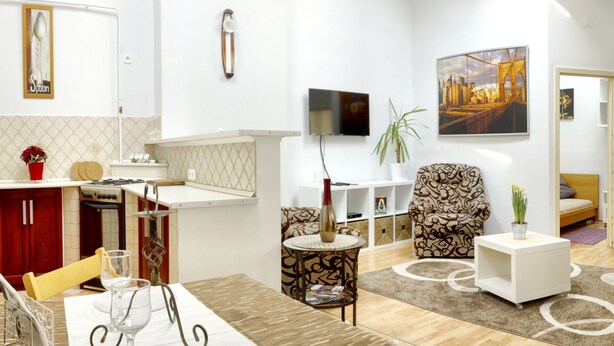 A modern living room with a sofa, armchair, and a TV mounted on the wall. -  AWESOME loc'n by Operahouse, charming Apartment, Lux on budget (Budapest)