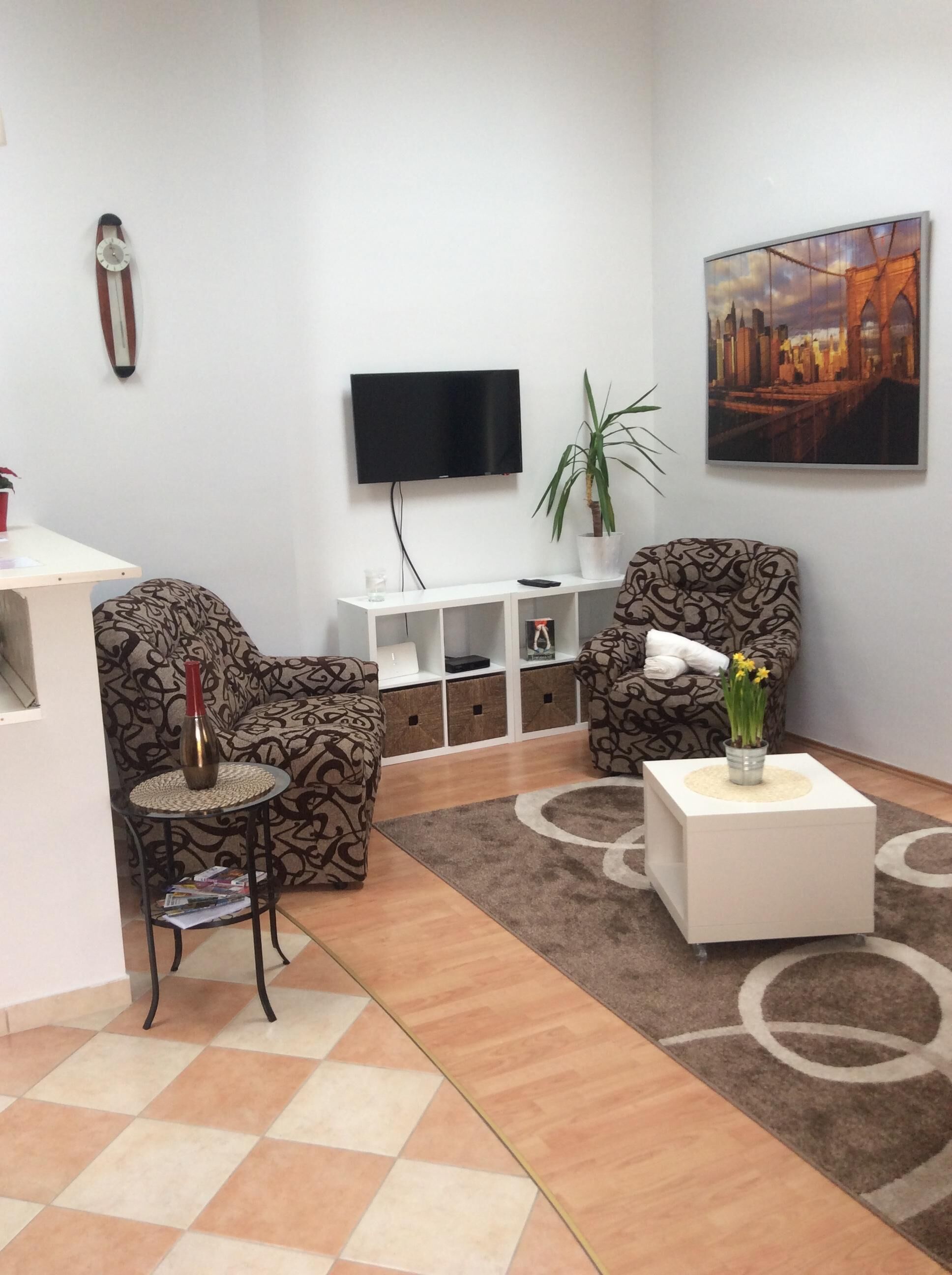 A living room with patterned sofas, a coffee table, a TV, a plant, and a painting.