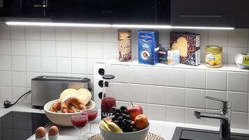 Une cuisine avec un saladier de fruits, un grille-pain, une machine à café et divers aliments sur le plan de travail.