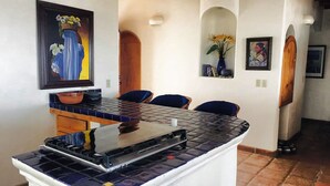A kitchen with a tiled backsplash, a stove, and a dining area with chairs and a table.