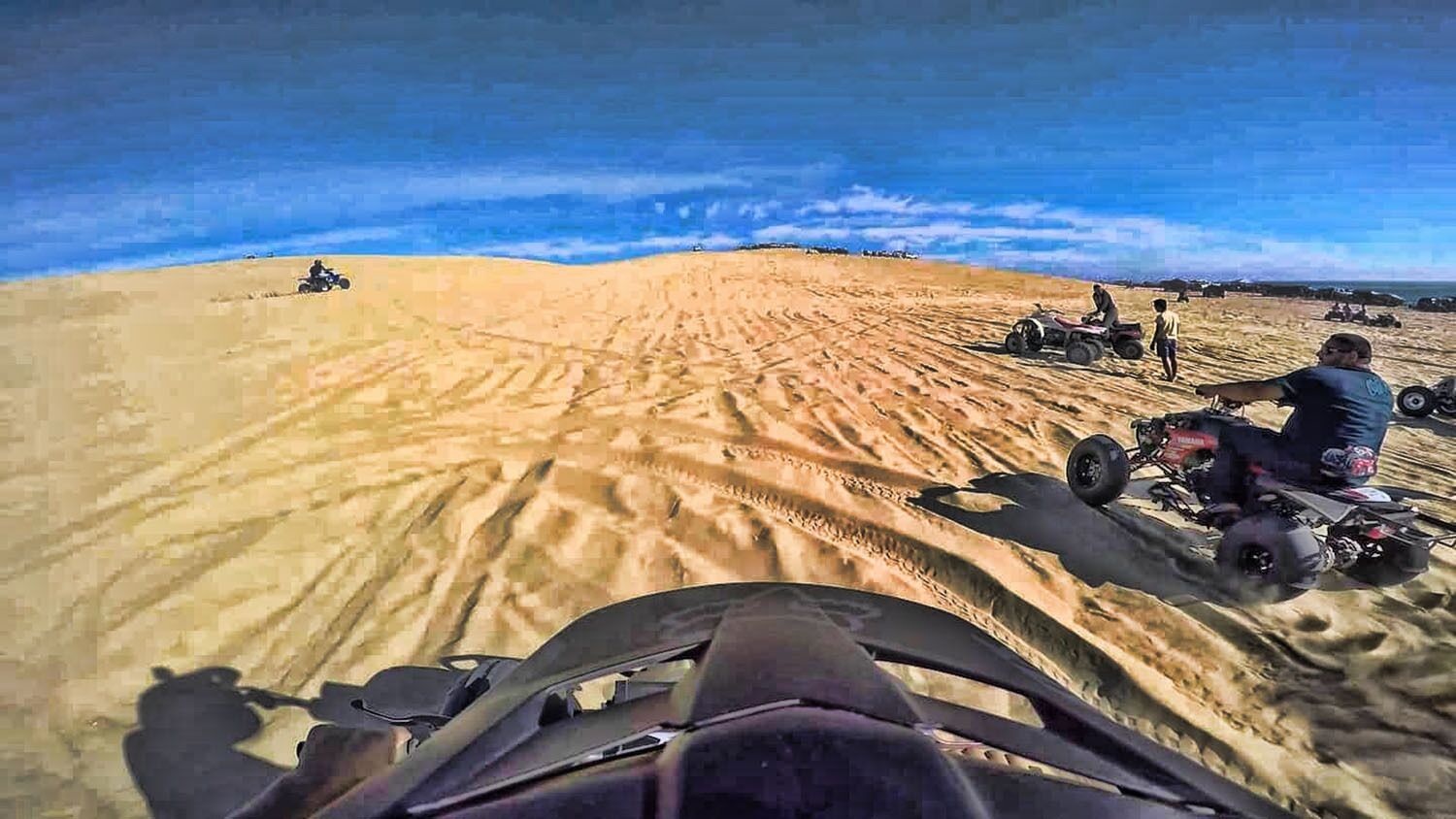 Wüstenlandschaft mit Quads und Personen.