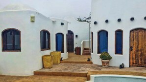 A white-walled building with a pool, steps leading to a door, and a small garden area.