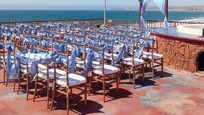 An outdoor seating area with rows of chairs, a flagpole with a flag, and a stage with draped fabric. - Casa Brisa Mar - Ocean front - Pool - Jacuzzi - Fire Pit (Primo Tapia (Cantamar area))
