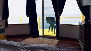 A room with a bed, a dresser, a painting, and a view of the sea through a large window. - Casa Brisa Mar - Ocean front - Pool - Jacuzzi - Fire Pit (Primo Tapia (Cantamar area))