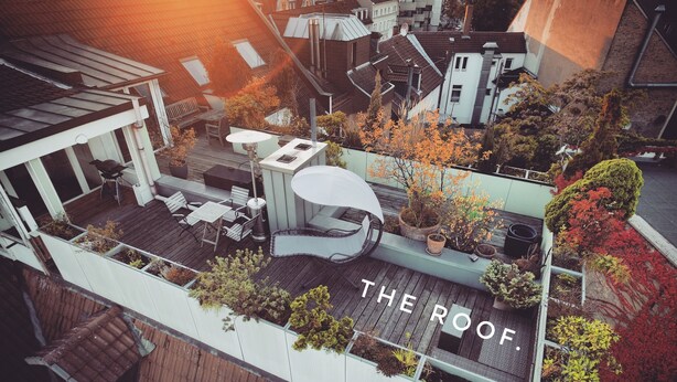 An aerial view of a rooftop with a dining area, outdoor seating, and various potted plants. - THE ROOF Penthouse in the heart of Karlsruhe (Karlsruhe)