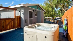 Ein Whirlpool auf einer Holzterrasse mit Überdachung und Holzzaun.