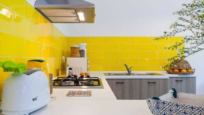 Una cocina con baldosas amarillas, una estufa a gas, un fregadero y una cesta de fruta.
