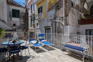 Une terrasse extérieure avec une table ronde, deux chaises longues et un banc en métal.
