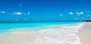 A beach with clear turquoise water and white sand.