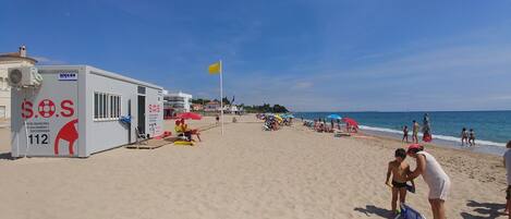 A beach with a lifeguard station, umbrellas, and people enjoying the sand and sea.