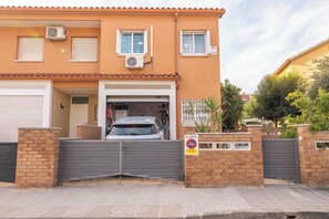 A two-story residential building with a gated entrance, a garage, and a balcony.