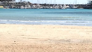 Une plage avec une marina en arrière-plan.