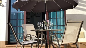 Une terrasse extérieure avec une table, des chaises et un grand parasol.