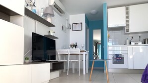 Une cuisine moderne avec des meubles blancs, un four encastré et un coin repas comprenant une table et des chaises.