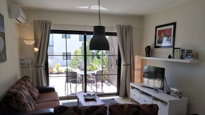 A living room with a sofa, TV, and a balcony with plants. -  "A true haven"  spacious Apartment in a small quiet complex nearby the beach (Puerto del Carmen)