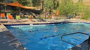Una piscina con agua azul cristalina, rodeada de sillas de descanso y sombrillas.