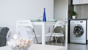 A modern kitchen with a dining table, chairs, a washing machine, and a bowl of fruit. - Ocean View apartments. Beachfront Ocean view terrace. Wifi. Parking (Gran Tarajal)